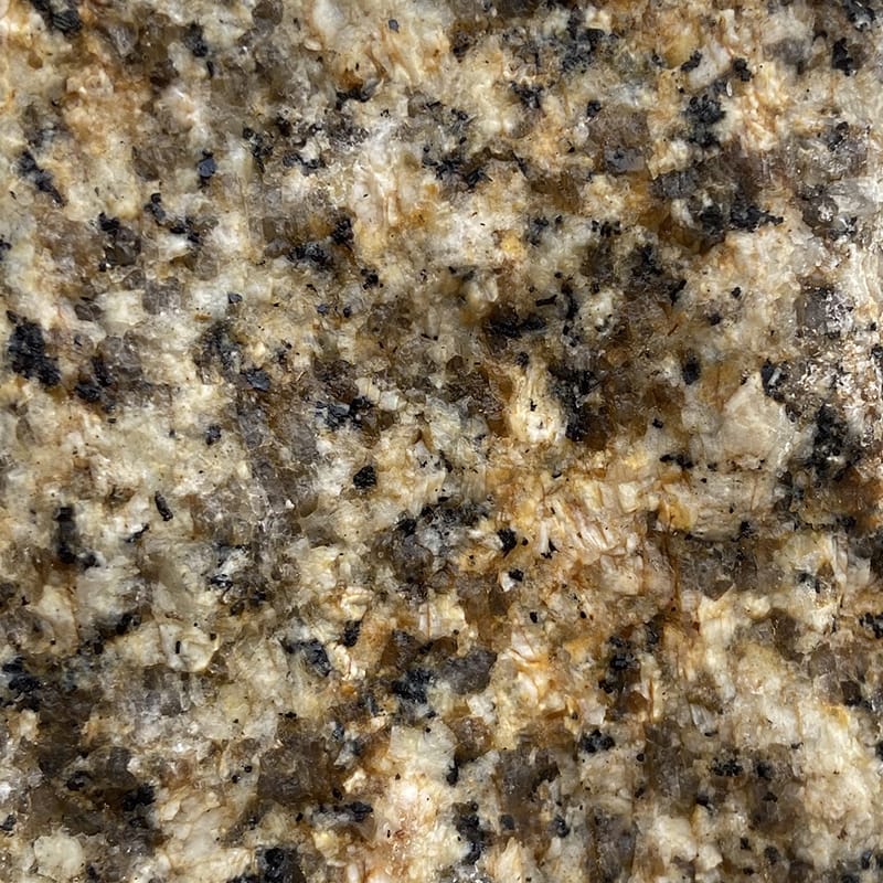 Close-up of a granite countertop featuring yellow-grey tones with distinct black and white speckles