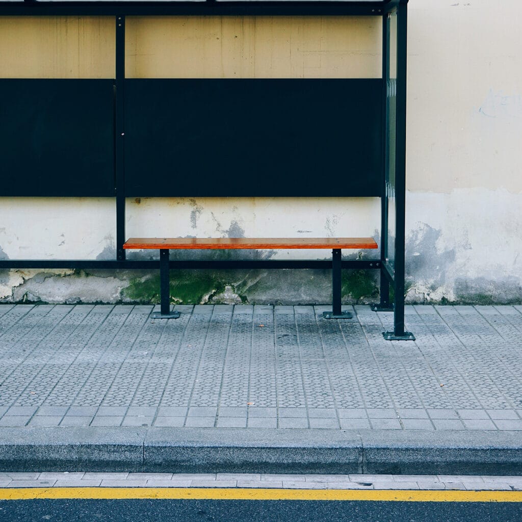 A bus stop with a bench in front, framed by granite kerbs, providing a resting spot for commuters