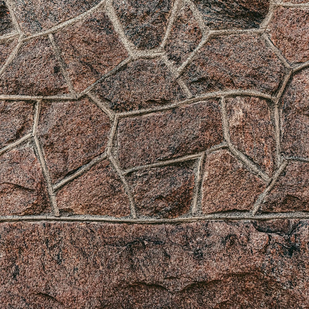 Close-up of a wall featuring a granite red vanga stone pattern, showcasing rich textures and colors