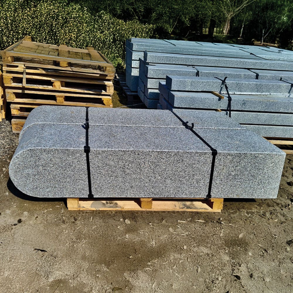 A large gray granite palisades with a rounded top, resting on wooden pallets, ready for transporting