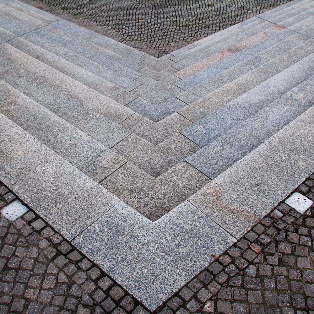 Granite steps lead down to a cobblestone surface, forming a V-shape with precise lines and angles, perfect for this public place