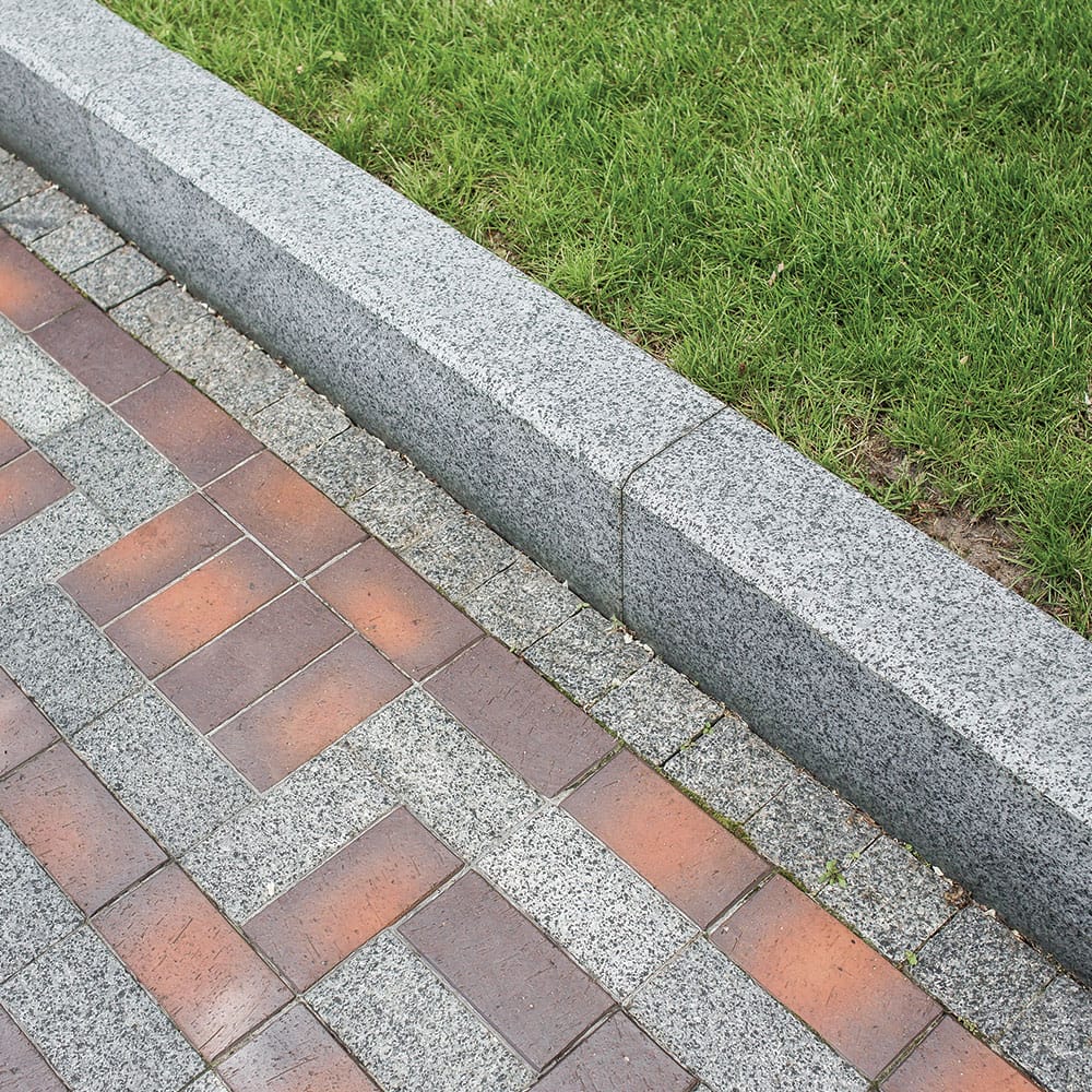 A brick walkway in a public square, complemented by granite kerbs for a cohesive design