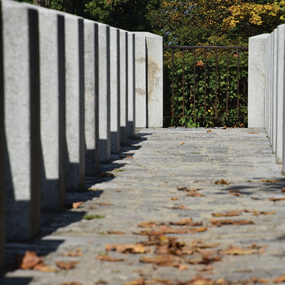 A peaceful enterance path lined with palisade retaining walls and a fence, creating a tranquil atmosphere