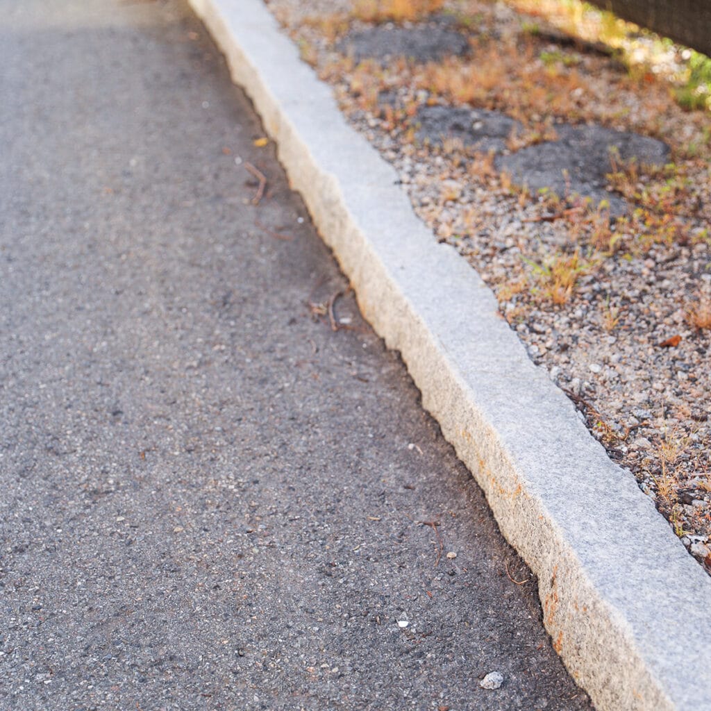 A granite kerb along the roadside, highlighting urban infrastructure