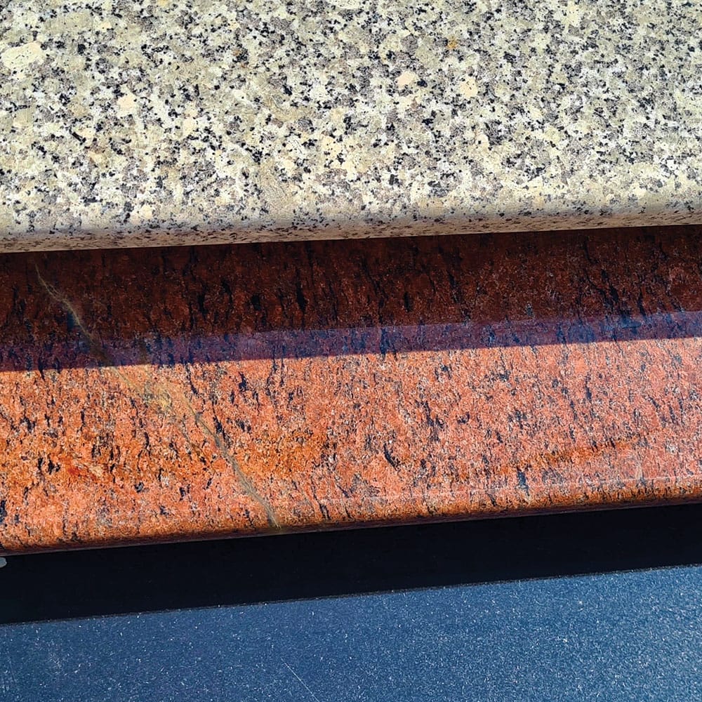 A stack of polished granite steps on a black and white table, showcasing various colors of granite window sills.